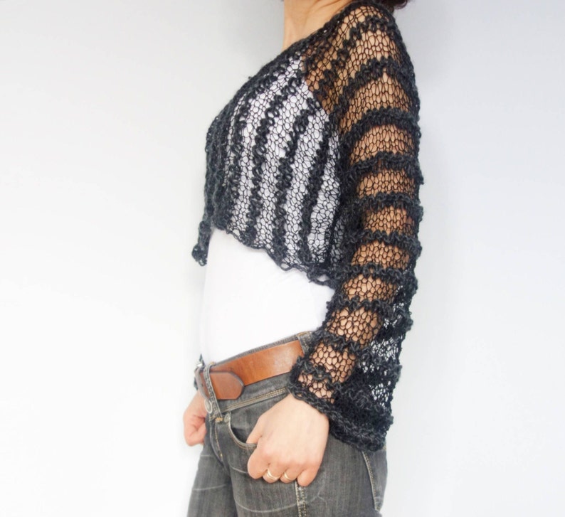 May include: Black crochet top with long sleeves and a striped pattern. The top is cropped and has a loose fit.