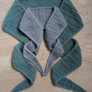 以下が含まれることがあります： 黒い持ち手と「But First, Coffee」のテキストが太字の黒で書かれた白いセラミックマグ。マグカップはぼやけた背景に置かれており、居心地の良い環境を示唆しています。マグカップの高さは約10cmです。