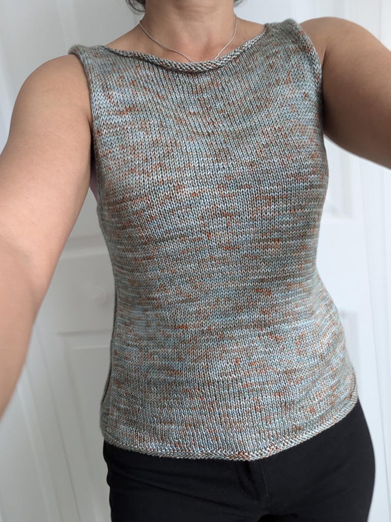 May include: A sleeveless knit top in a speckled pattern of blue, brown, and gray. The top has a scoop neckline and a fitted silhouette. The fabric appears to be a soft, lightweight yarn, suitable for warmer weather.