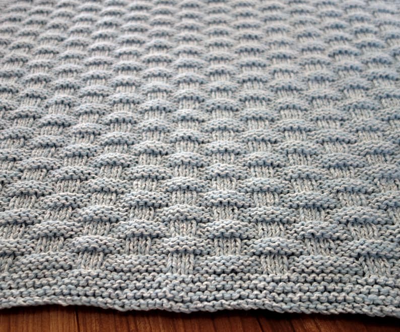 May include: A light blue knitted blanket with a checkered pattern.