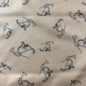 May include: Cream-colored fabric with a repeating pattern of navy blue dog illustrations. Each dog is depicted holding a small flag. The fabric has a textured appearance.