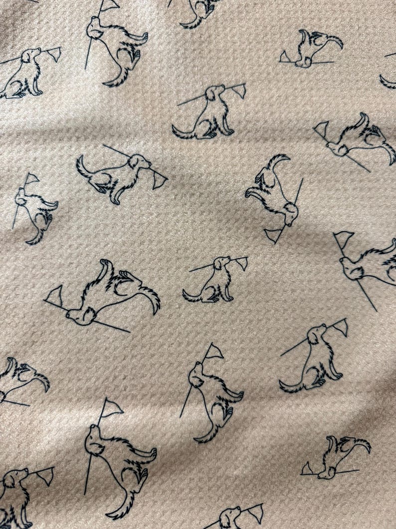 May include: Cream-colored fabric with a repeating pattern of navy blue dog illustrations. Each dog is depicted holding a small flag. The fabric has a textured appearance.