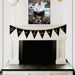 May include: Black and gold graduation banner with the word "graduate" in gold lettering. A black and gold sign with the text "Congrats Grad" and a photo of a graduate. The sign is hanging above a fireplace.