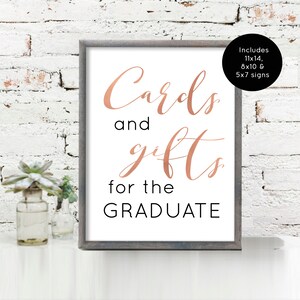 May include: A white sign with a gray frame, reading "Cards and gifts for the GRADUATE" in black text. The words "Cards" and "gifts" are written in a rose gold script font. The sign includes 11x14, 8x10, and 5x7 signs.