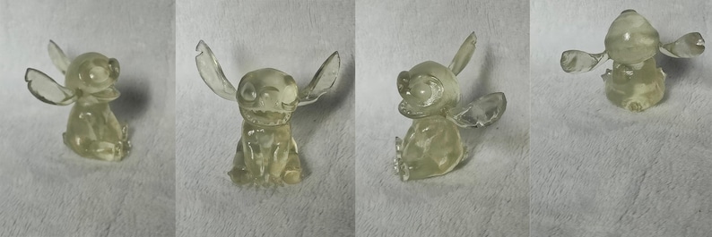 Puede incluir: Una figurita de Stitch azul transl&uacute;cida con orejas grandes y una amplia sonrisa. La figurita est&aacute; sentada con las piernas cruzadas y los brazos cruzados.