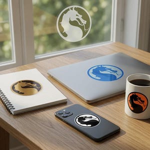 May include: A wooden table displays items with a dragon logo. These include a notebook, laptop, smartphone, and a coffee mug. The dragon logo is in gold, blue, black, and orange. The items are arranged near a window.