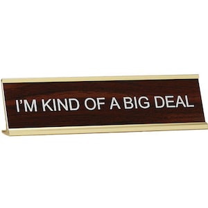 May include: A brown desk nameplate with a gold trim and the text "I'm kind of a big deal" in white lettering.