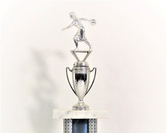 May include: Silver trophy with a female figure holding a bowling ball on top. The base is marble with a blue and silver patterned column and a crown and eagle emblem. The base has the inscription "Mixed L.G. 1970-71".