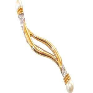 Pu&ograve; includere: Un fermaglio dorato con un design curvo a doppio anello. Il fermaglio &egrave; decorato con piccole pietre trasparenti e due accenti di perle finte.