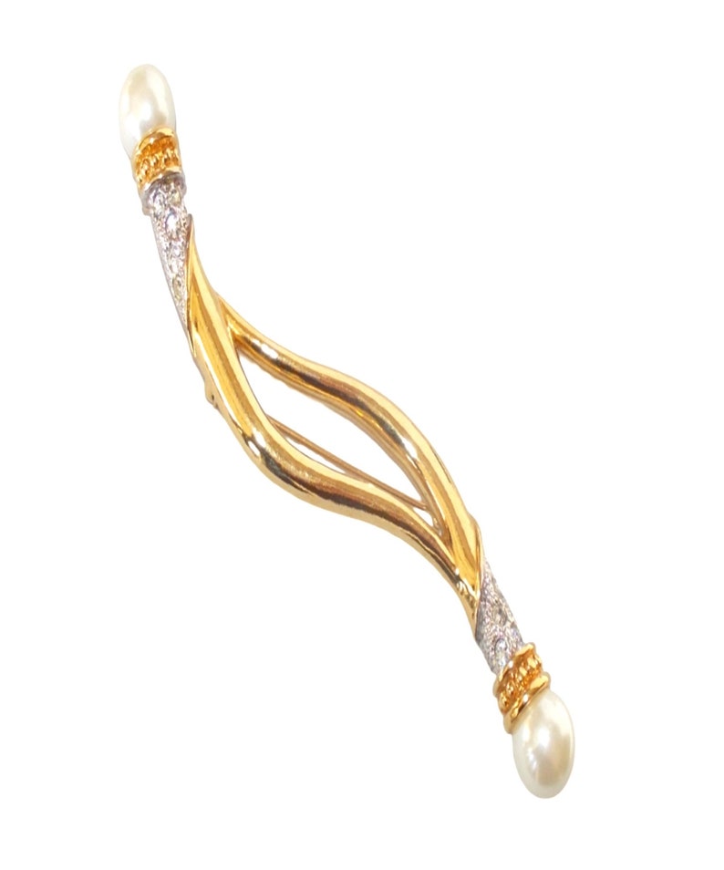 Pu&ograve; includere: Un fermaglio dorato con un design curvo a doppio anello. Il fermaglio &egrave; decorato con piccole pietre trasparenti e due accenti di perle finte.