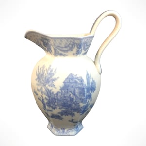 May include: A white ceramic pitcher with a blue and white floral pattern. The pitcher has a handle and a spout.