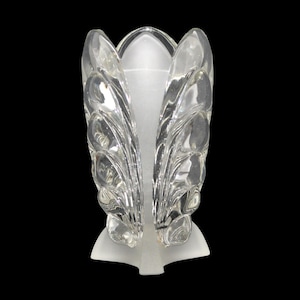 May include: A clear glass vase with a frosted white base and a decorative design of overlapping leaves. The vase has a unique, organic shape.