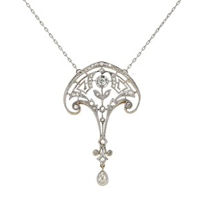 Könnte beinhalten: Eine Halskette aus Silber und Gold mit einem zarten Anhänger, der ein florales Design und einen tropfenförmigen Diamanten zeigt.