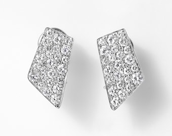 May include: A pair of silver-toned stud earrings featuring an asymmetrical, trapezoidal shape. The surface of each earring is densely encrusted with numerous small, clear, round-cut stones that create a highly reflective, sparkling appearance.