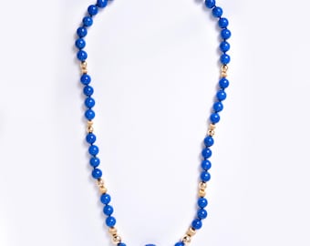 May include: A necklace featuring a series of round, vibrant blue beads interspersed with smaller, textured gold-toned spherical beads. The strand culminates in a single, larger, carved blue bead shaped like a flower at the center point.