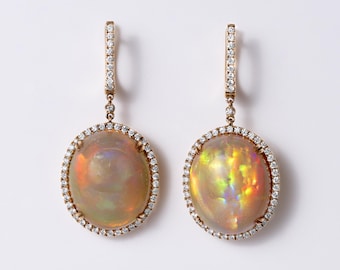 May include: A pair of drop earrings featuring large oval-shaped opals with iridescent flashes of orange, yellow, and green. Each opal is surrounded by a halo of small round white diamonds, with additional diamonds set along the vertical earring posts.