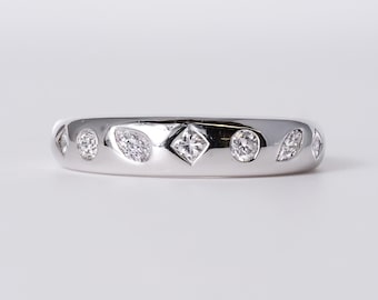 May include: A polished silver-toned band ring featuring a series of flush-set clear stones in various shapes, including round, marquise, and a central square-cut stone, arranged horizontally across the front surface of the metal band.