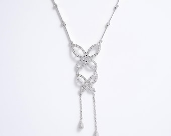 May include: A silver-toned necklace featuring a central pendant composed of two stacked, openwork butterfly shapes with textured surfaces. The chain includes small, evenly spaced circular links, and the pendant ends in two delicate dangling chains.