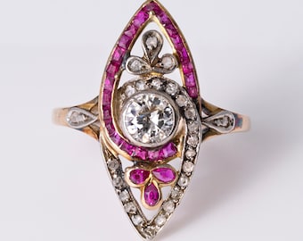 May include: A marquise-shaped ring crafted from yellow gold and silver, featuring a central round brilliant-cut diamond surrounded by a border of channel-set rubies and smaller pavé-set diamonds, with additional ruby accents at the base.