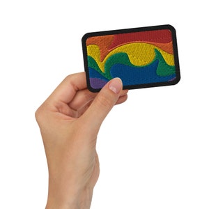 Pode incluir: Um patch retangular bordado com um design de onda arco-íris. O patch apresenta uma borda preta e um espectro vibrante de cores, incluindo vermelho, laranja, amarelo, verde, azul e roxo. O design é um símbolo do orgulho LGBTQ+.