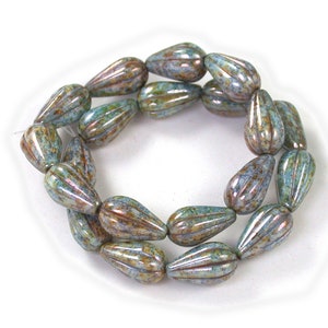 May include: A strand of teal blue and brown glass beads with a ribbed texture. The beads are shaped like teardrops.