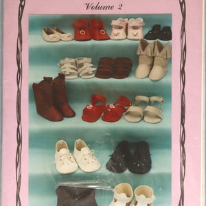 May include: A pink package titled "Cobbler's Bench Volume 2" featuring various miniature shoe styles in multiple colors. The shoes include boots, sandals, and Mary Janes. The package also includes the text "Yesterday's Children".