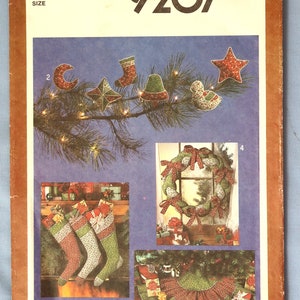 May include: Simplicity 9207 sewing pattern featuring Christmas ornaments, stockings, a wreath, and a tree skirt. The ornaments include a star, bell, and crescent moon. The pattern is for one size.