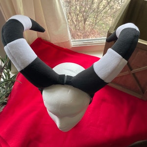 May include: Black and white striped headband with a foam head form. The headband is made of soft, plush fabric.