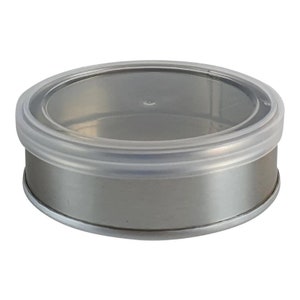 May include: A round, silver-colored metal container with a clear plastic lid. The lid fits snugly over the container, creating a seal. The container is designed for storage and is suitable for various items.