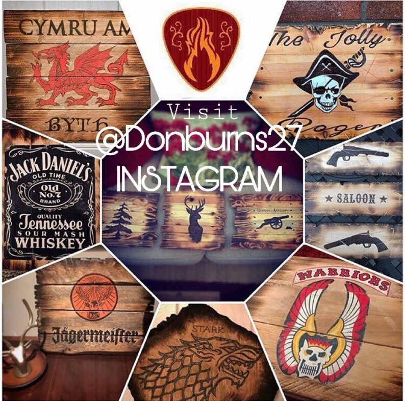 May include: A collection of rustic wooden signs with various designs. The signs feature images of a dragon, a skull, a deer, a cannon, and text including "CYMRU AM", "The Jolly Roger", "Jack Daniel's", "Saloon", "J&auml;germeister", "STARK", and "WARRIORS".