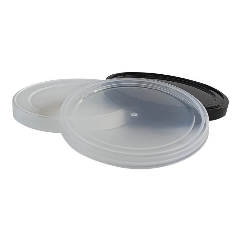 May include: Three clear plastic lids of varying sizes. One lid is black, and the other two are translucent. The lids are round and appear to be made of a lightweight plastic material. The lids are stacked on top of each other.