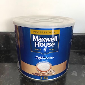 Peut inclure: Une boîte bleue et dorée de cappuccino Maxwell House Professional. La boîte est étiquetée avec le logo Maxwell House et les mots "Professional", "Since 1892", et "Cappuccino". Une image d'une tasse de cappuccino est représentée sur la boîte. La boîte est de 1 kg.