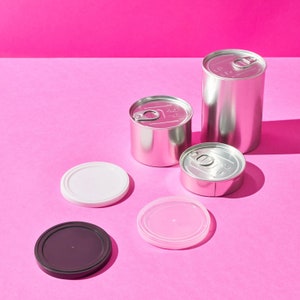 May include: An assortment of shiny, silver metal cans of varying sizes, some with pull-tab lids, and several plastic lids in white, pink, and dark brown. The items are arranged on a bright pink background.