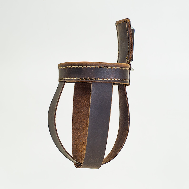 May include: A brown leather bottle holder with a stitched top and a strap. The holder is designed to hold a bottle upright.