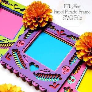 May include: A layered, colorful Papel Picado frame with a blue center, adorned with skull and floral cutouts. The frame is purple, with pink, yellow, and green accents. The image also features orange paper flowers and the text "FPbyVee Papel Picado Frame SVG File."