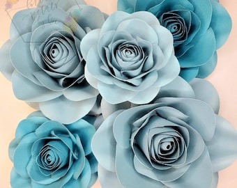 May include: Five light blue paper roses with a layered, curled center. The roses are arranged in a cluster, with the largest rose in the center.
