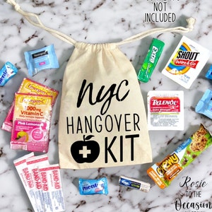 Könnte beinhalten: Eine weiße Stofftasche mit einem schwarzen Apfel- und Pluszeichen-Motiv und dem Text "NYC Hangover Kit". Die Tasche ist gefüllt mit verschiedenen Artikeln, darunter ein Pflaster-Paket, ein Tylenol-Paket, ein Emergen-C-Paket, ein Shout-Feuchttuch-Paket, ein Kaugummi-Paket und ein Pfefferminz-Paket.