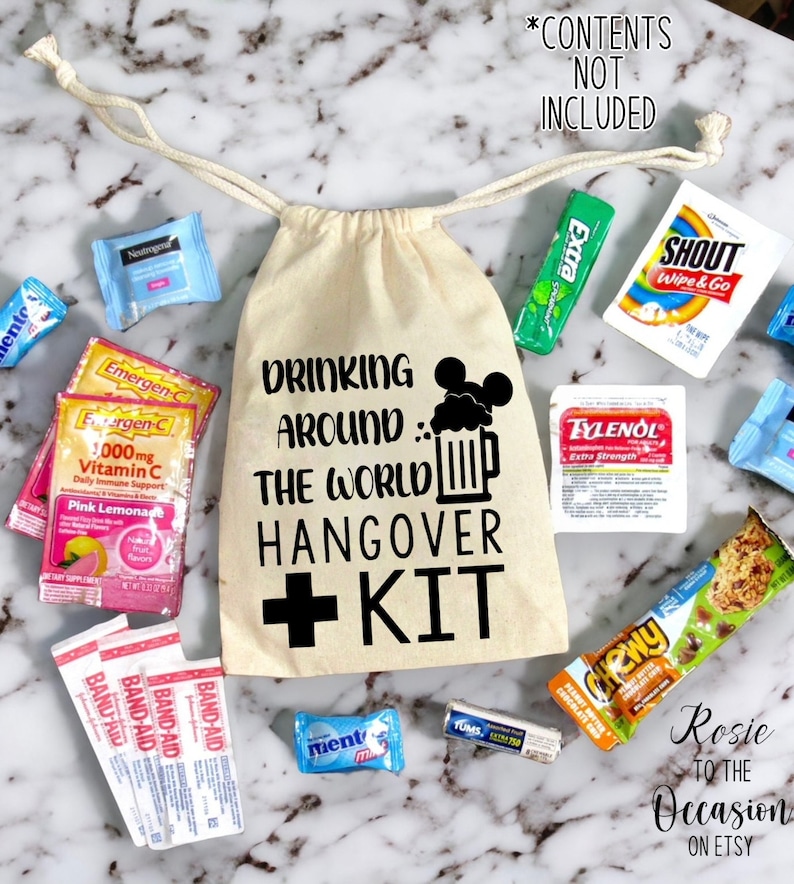 K&ouml;nnte beinhalten: Eine wei&szlig;e Kordeltasche mit dem Aufdruck "Drinking Around The World Hangover Kit". Die Tasche ist gef&uuml;llt mit verschiedenen Artikeln, darunter Pflaster, Tums, Emergen-C-P&auml;ckchen und eine kleine Flasche Tylenol.