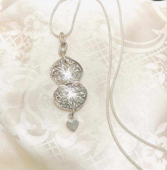 Three hearts together. Two handmade fine silver adjoined hearts with a small heart dangling. One of a kind.