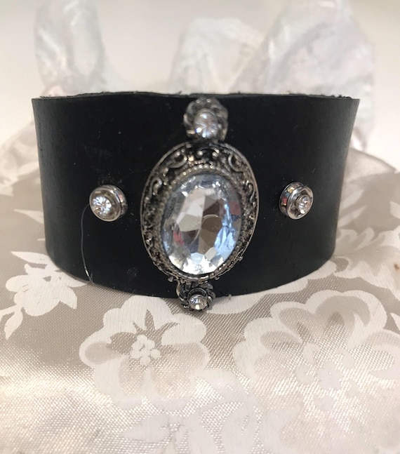 Leather cuff with large vintage appearing diamond surrounded by4 small crystals. Unique one of a kind. Adjustable size from 71/2 to 8 inches
