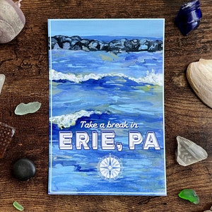 May include: A blue and white postcard with a painting of a seascape. The text on the postcard reads "Take a break in ERIE, PA". A compass is in the bottom center of the postcard.