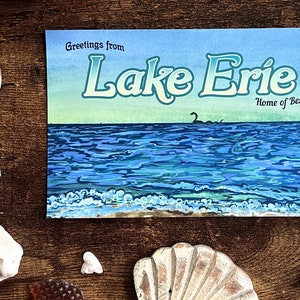 May include: A postcard with a blue and green watercolor painting of Lake Erie. The text "Greetings from Lake Erie" is at the top of the postcard. The text "Home of Bessie" is at the bottom of the postcard.
