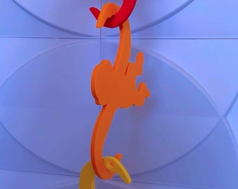 Puede incluir: Esculturas tridimensionales de monos coloridos en rojo, naranja y amarillo están unidas, colgando contra una pared azul claro texturizada. Los monos son estilizados y juguetones, creando un elemento decorativo caprichoso.