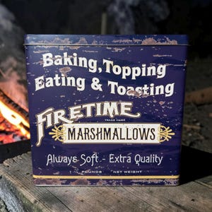 May include: A rectangular blue tin with the words "Baking, Topping, Eating & Toasting" and "FIRETIME MARSHMALLOWS" in white. The tin reads "Always Soft - Extra Quality" and "1 Pounds Net Weight". The tin has a rustic, distressed appearance.