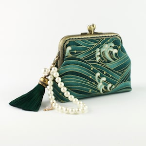 May include: A green and gold fabric purse with a wave pattern and a pearl and tassel chain. The purse has a brass clasp and a gold trim.