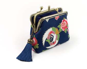 May include: A small blue fabric purse with a gold clasp and a tassel. The purse is decorated with a floral pattern and a crane design.