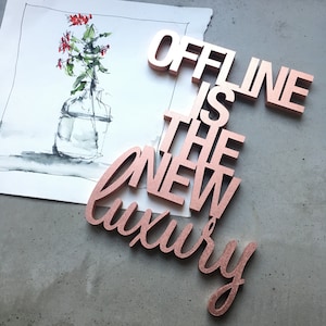 Könnte beinhalten: Holzbuchstaben in Roségold, die den Satz "Offline is the new luxury" buchstabieren.