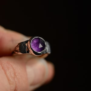 May include: A silver ring with a purple amethyst gemstone set in a bezel setting.