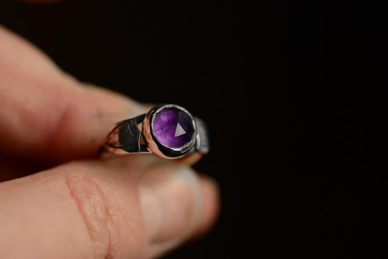 May include: A silver ring with a purple amethyst gemstone set in a bezel setting.