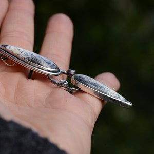 May include: A silver necklace with a pendant featuring two white and gray agate stones set in silver.
